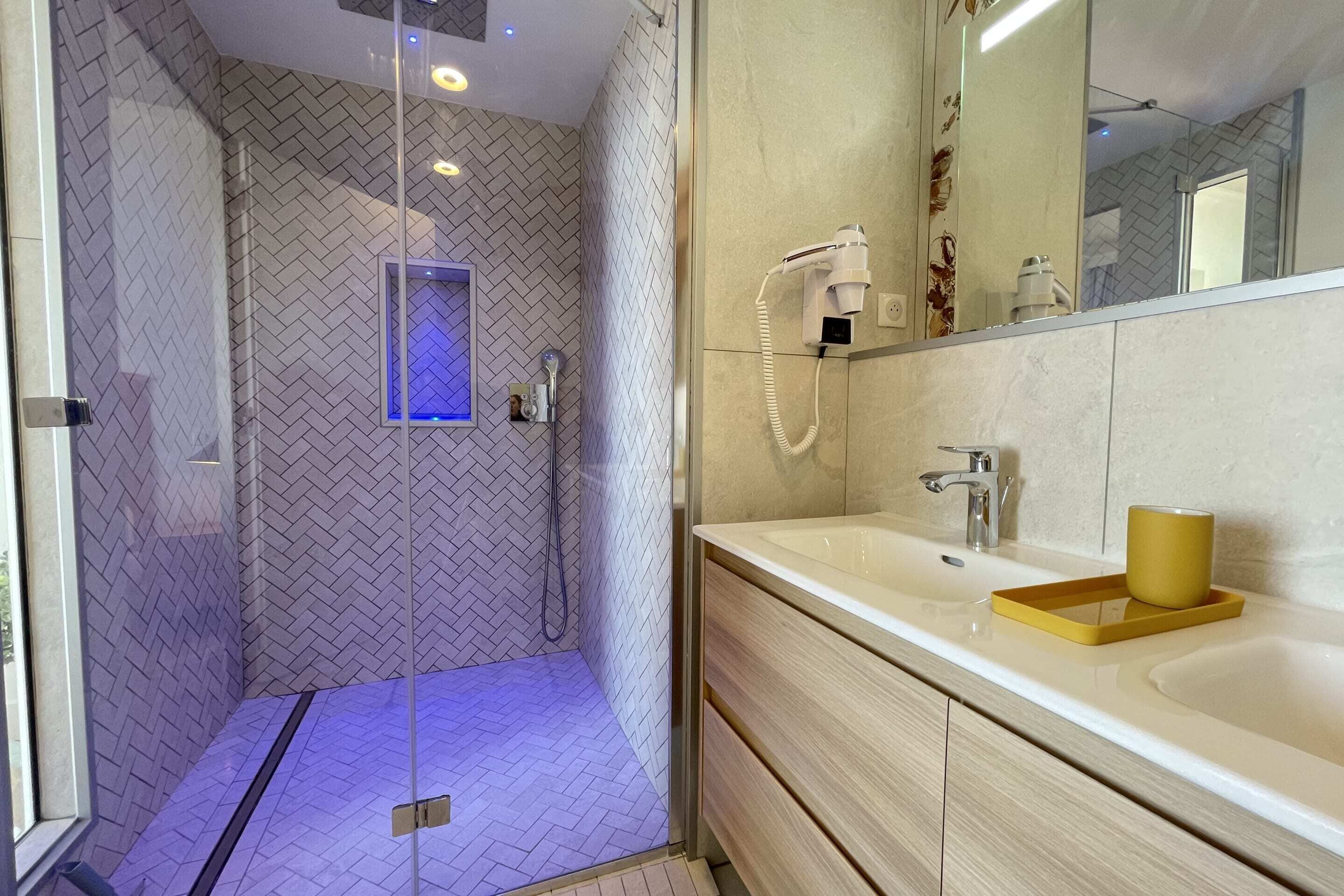 A modern bathroom with a glass-enclosed shower, a vanity with a sink, and a mirror.