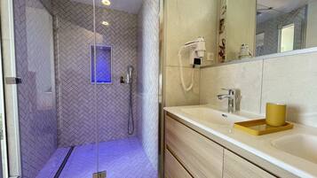 A modern bathroom with a glass-enclosed shower, a vanity with a sink, and a mirror.