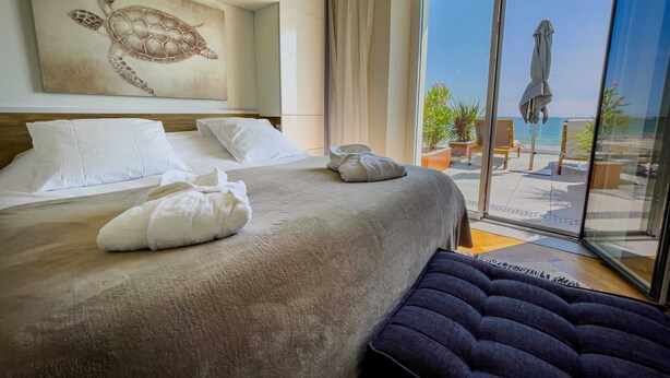 A hotel room with a large bed, a view of the beach, and a turtle artwork on the wall. - La maison Régent (Pornichet)
