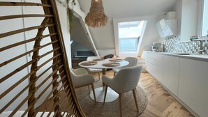 A modern kitchen with a round dining table, white cabinets, and a hanging light fixture. - La maison Régent (Pornichet)