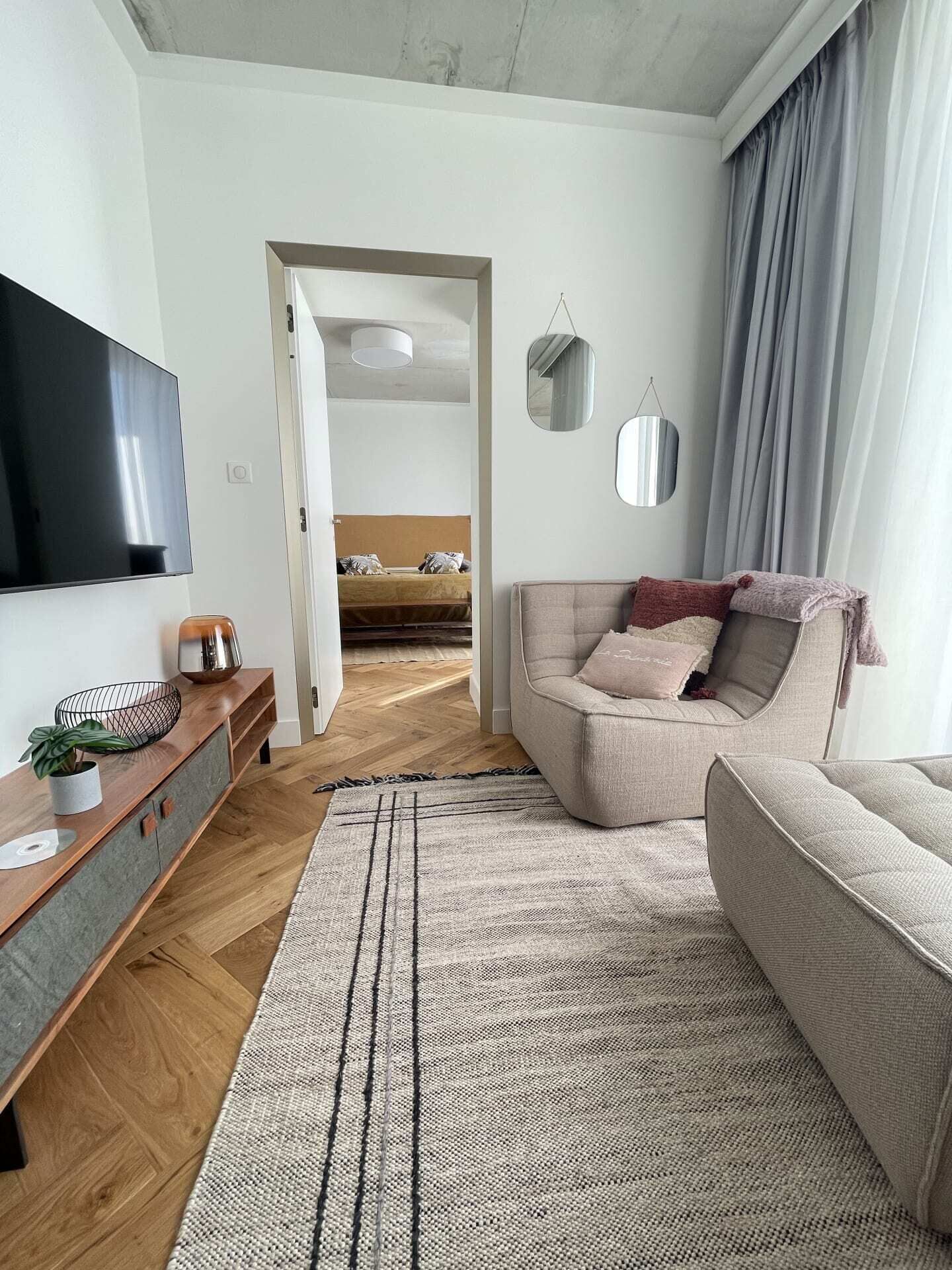 A modern living room with a sofa, a TV, a console table, and a view into another room.