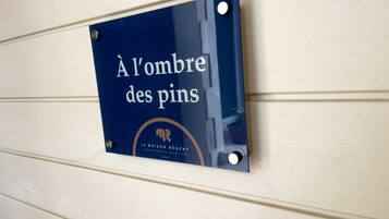 A sign with the text "À l'ombre des pins" and the logo of "la maison régent" on a wall.