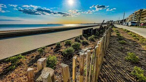 A coastal road with a wooden fence and plants, leading to a beach. - La maison Régent (Pornichet)