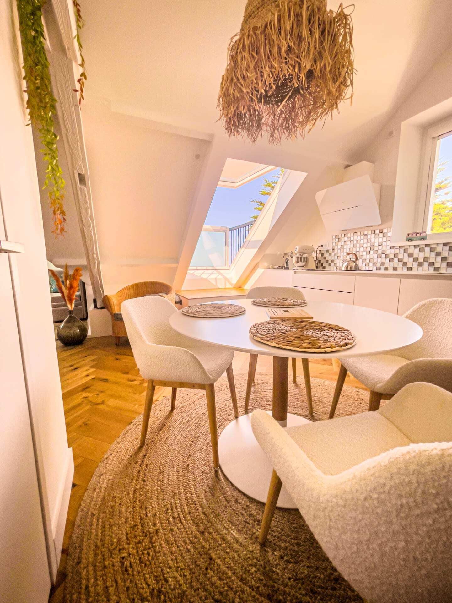 A modern dining area with a round table, white chairs, and a woven rug.