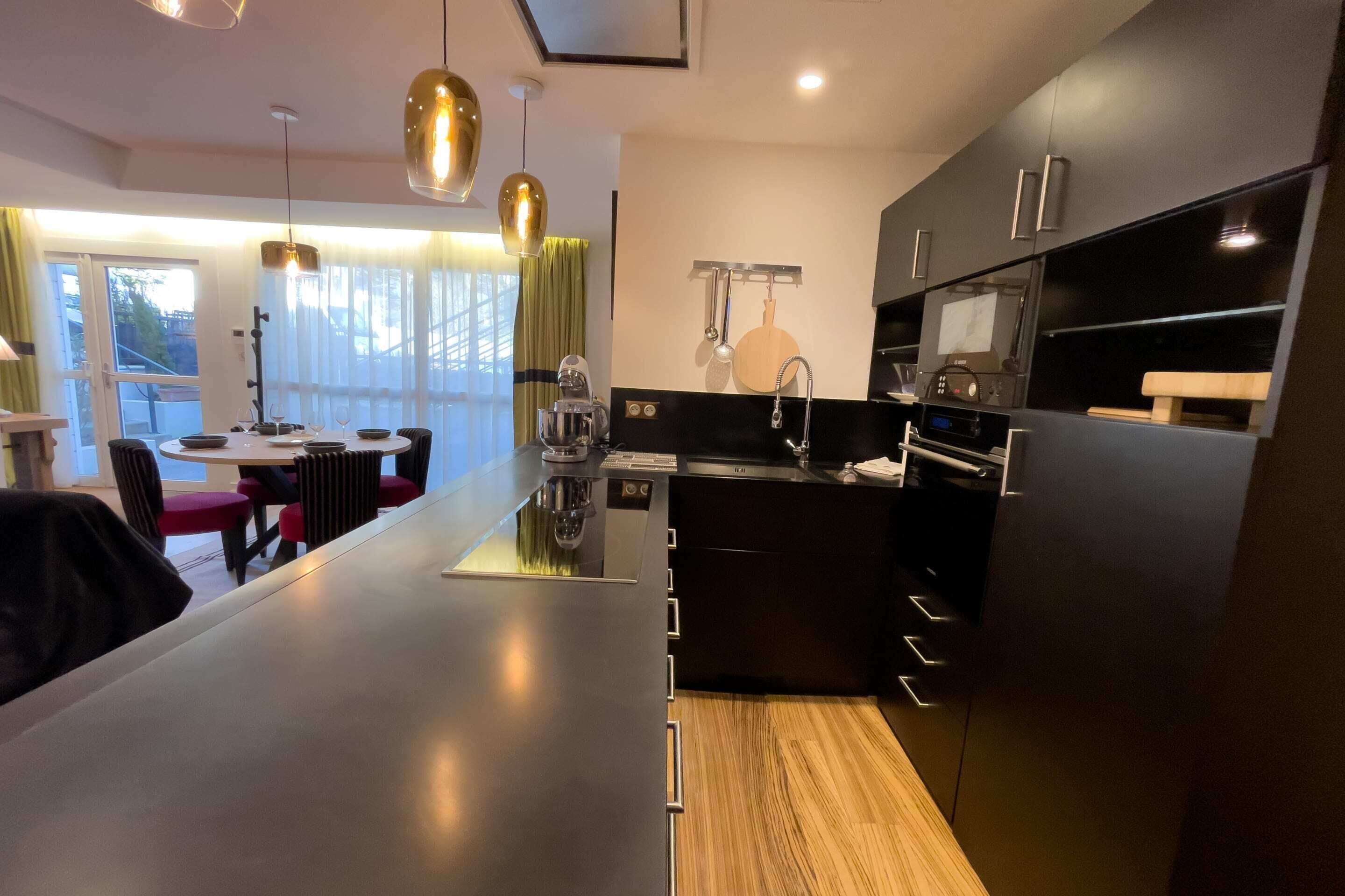 A modern kitchen with a central island, black cabinetry, and pendant lighting.