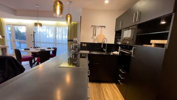 A modern kitchen with a central island, black cabinetry, and pendant lighting.