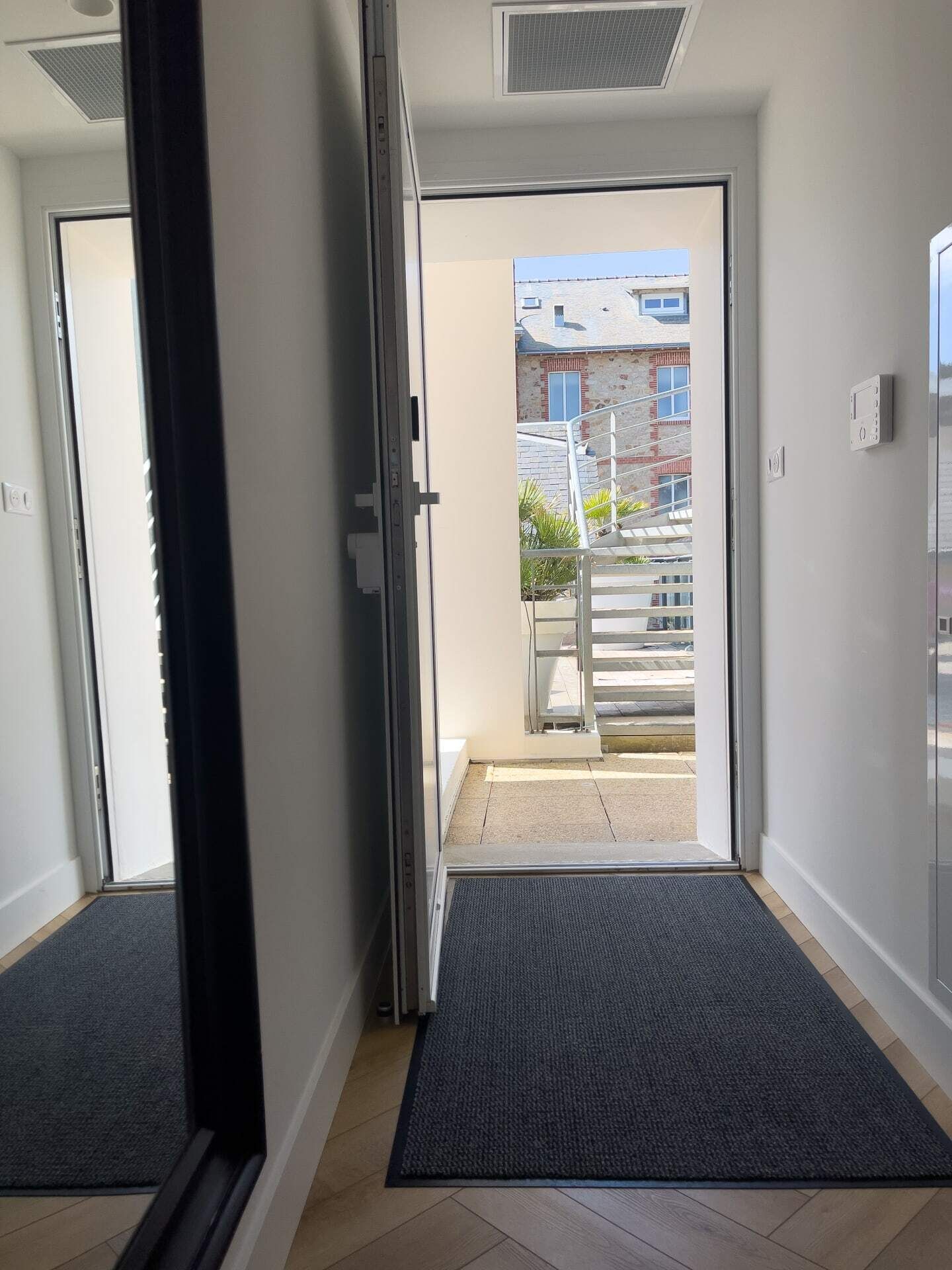 L’entrée d’un hôtel, avec une porte vitrée donnant sur l’extérieur.