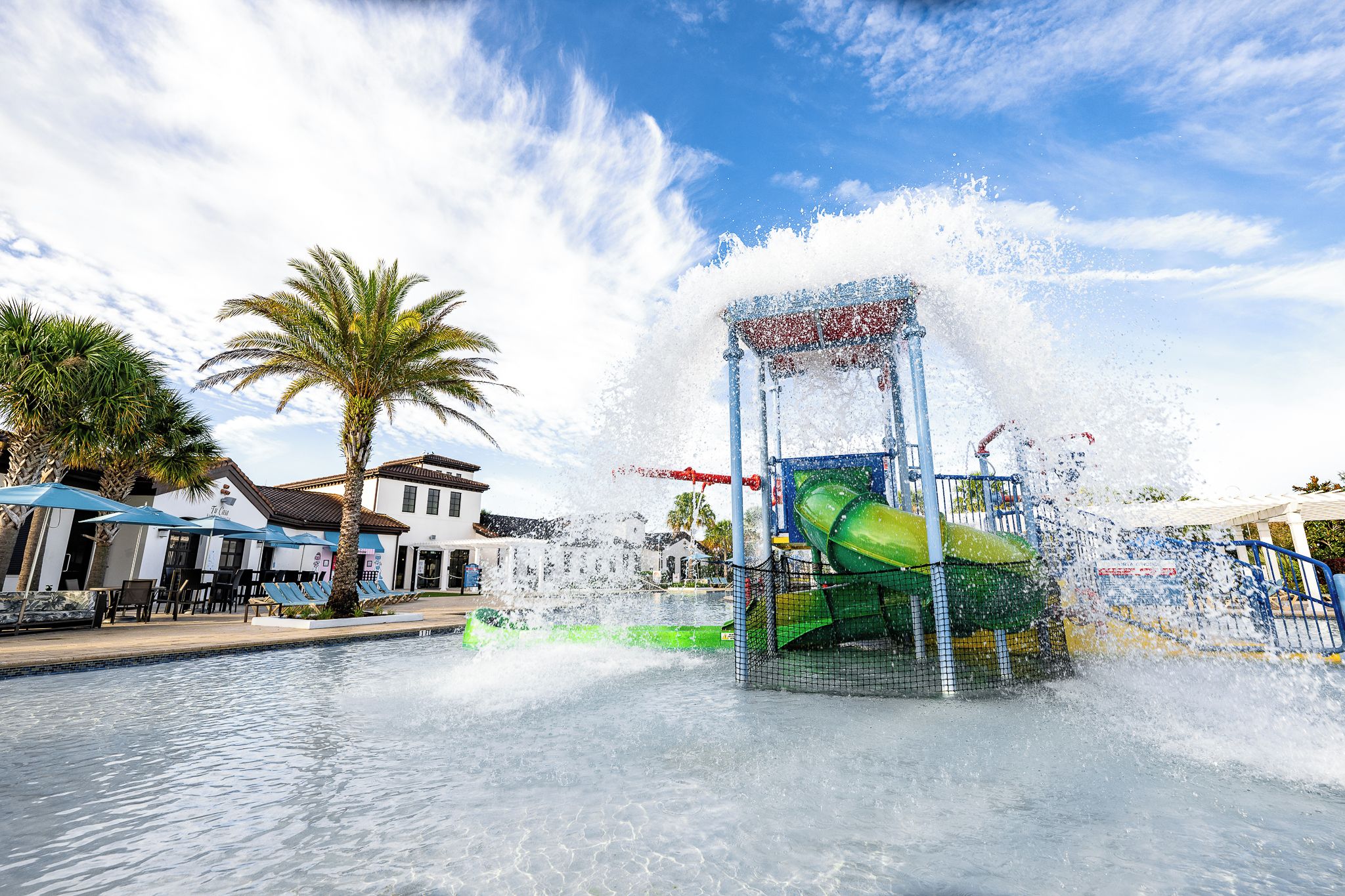 Un espace de jeux aquatiques avec un toboggan vert et une fontaine.