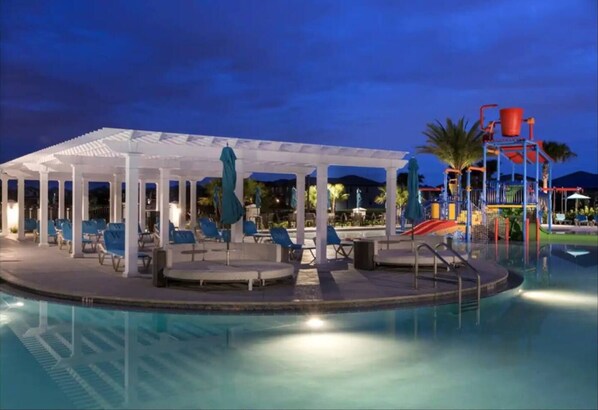 Relax by the pool surrounded by a covered seating area with lounge chairs and umbrellas.