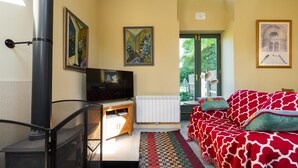 Une pièce confortable avec un canapé, un téléviseur, un radiateur et des œuvres d’art accrochées aux murs.
