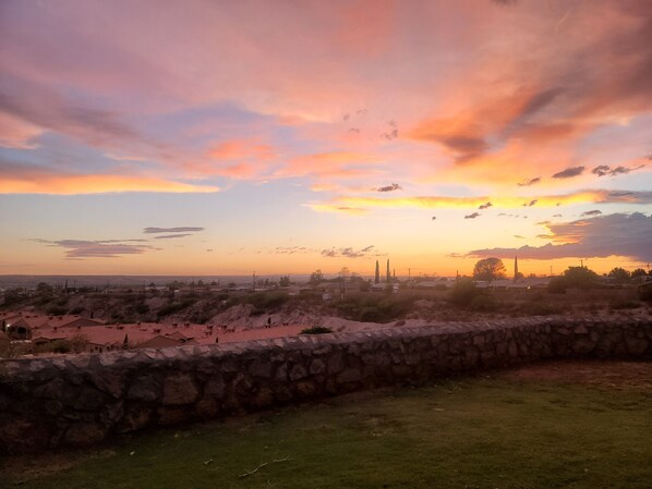 Ein Sonnenuntergang über einer ländlichen Landschaft mit Steinmauern und spärlicher Vegetation.