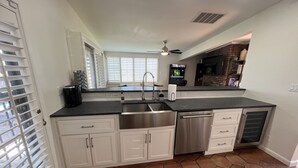 A kitchen with white cabinets, a stainless steel sink, and a black countertop.