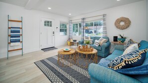 Ein modernes Wohnzimmer mit einem blauen Sofa, einem Korpus-Couchtisch und einem gemusterten Teppich.