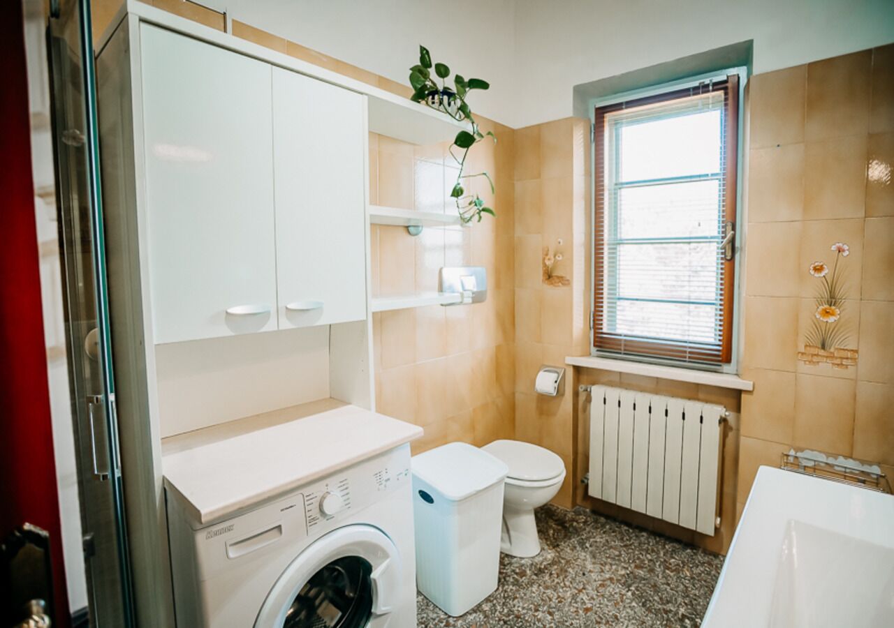 Un bagno compatto con lavatrice, wc e termosifone.