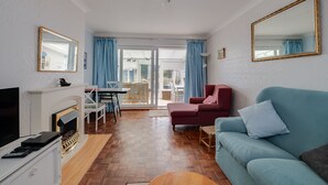 Una sala de estar con un sofá, televisión, chimenea y un comedor con mesa y sillas.