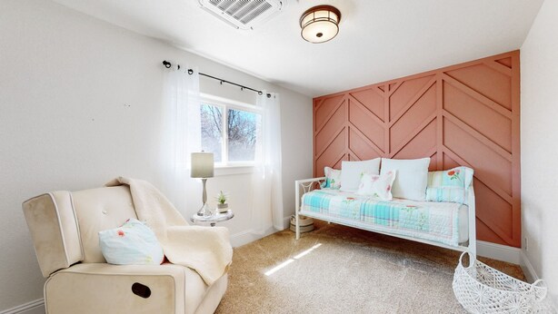Ein Schlafzimmer mit Bett, Stuhl, Lampe und Fenster.
