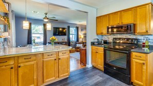 A modern kitchen with wooden cabinets, a large island, stainless steel appliances, and pendant lighting. - Pet-Friendly Pensacola Home w/ Sunny Backyard! (Pensacola)