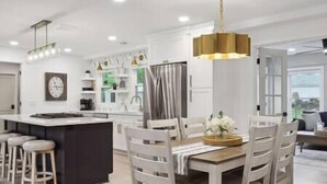 Une cuisine moderne dotée d’un îlot central, de tabourets de bar et d’une table à manger avec des chaises.