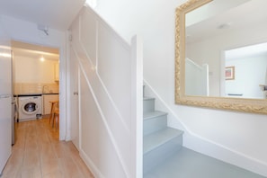 A clean, modern interior with a staircase, a washing machine, and a large mirror.