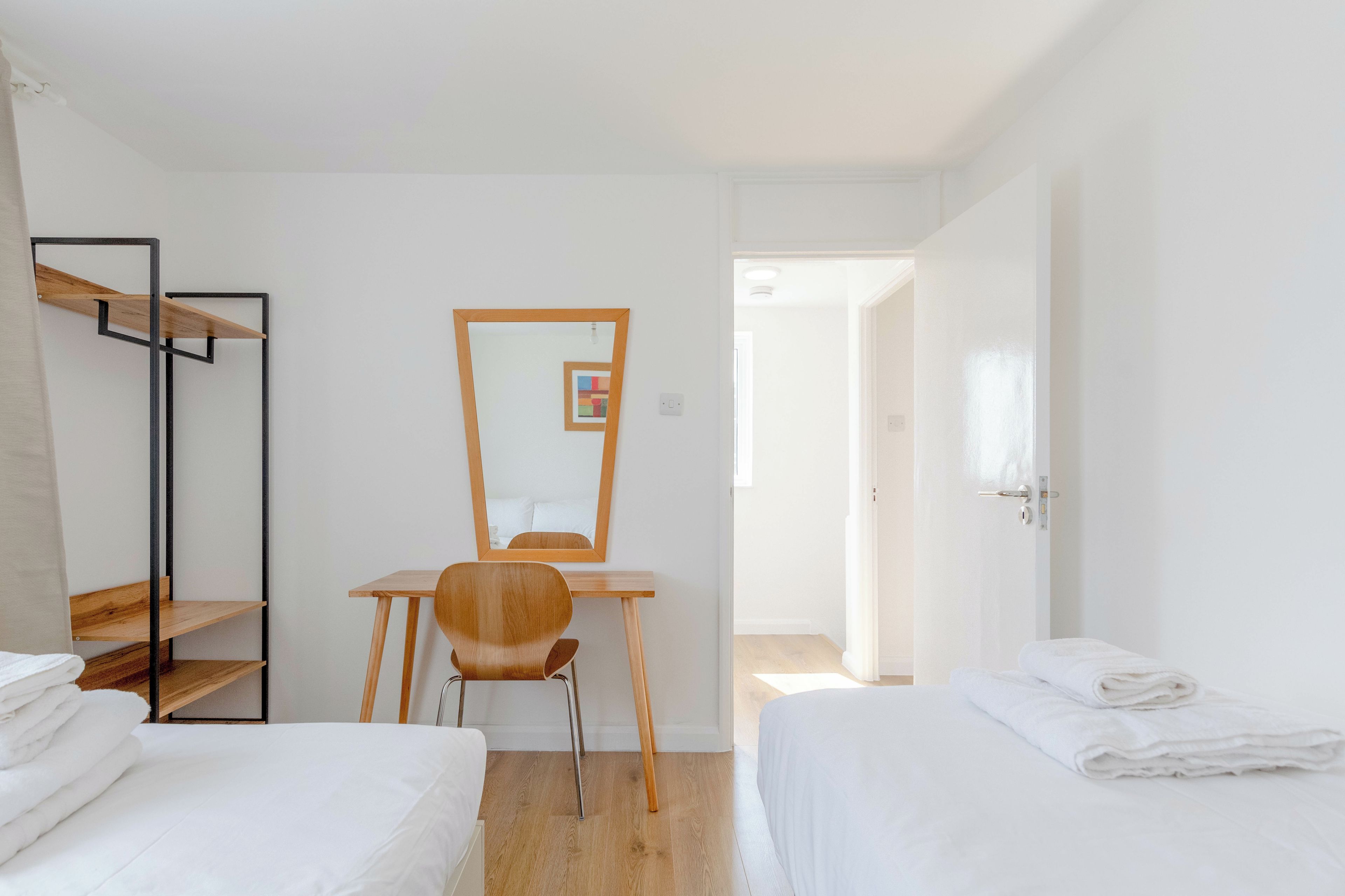 A hotel room with a wooden desk, a chair, a bed, and a wardrobe.