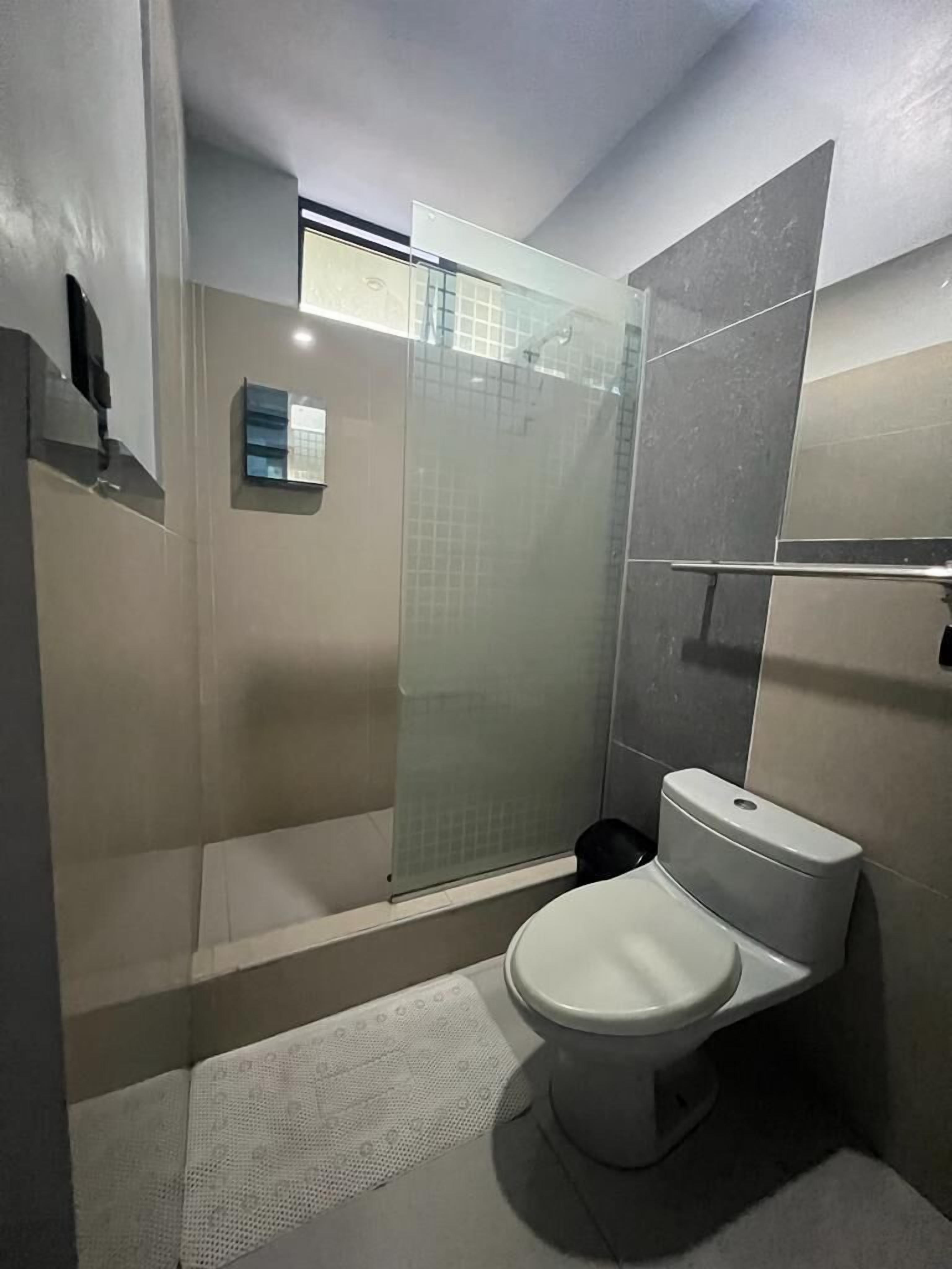 Un baño moderno con cabina de ducha de vidrio, inodoro y perchero para toallas.