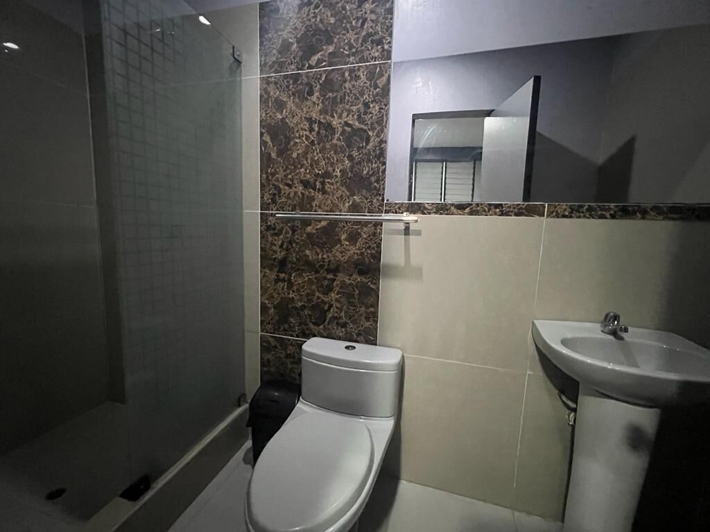 Un baño con inodoro, lavabo y zona de ducha.