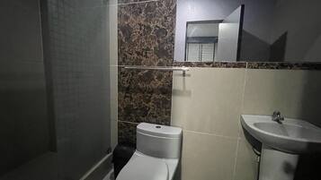 Un baño con inodoro, lavabo y zona de ducha.