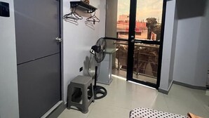 Een moderne kamer met een schuifdeur naar een balkon, een klein krukje, een ventilator en een laken met stippen.