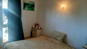 A bedroom with a bed, a dresser, a painting, and a wall-mounted light. - Arlozorov 3BD Apartment (Tel Aviv)
