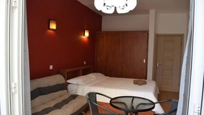 Een slaapkamer met een bed, een bank, een tafel en twee wandlampen.