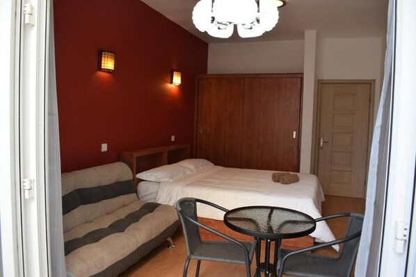 Une chambre à coucher comprenant un lit, un canapé, une table et deux lampes fixées au mur.