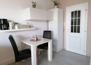 Cozy retreat with a white table and two chairs, a cabinet, and a door with a glass panel.