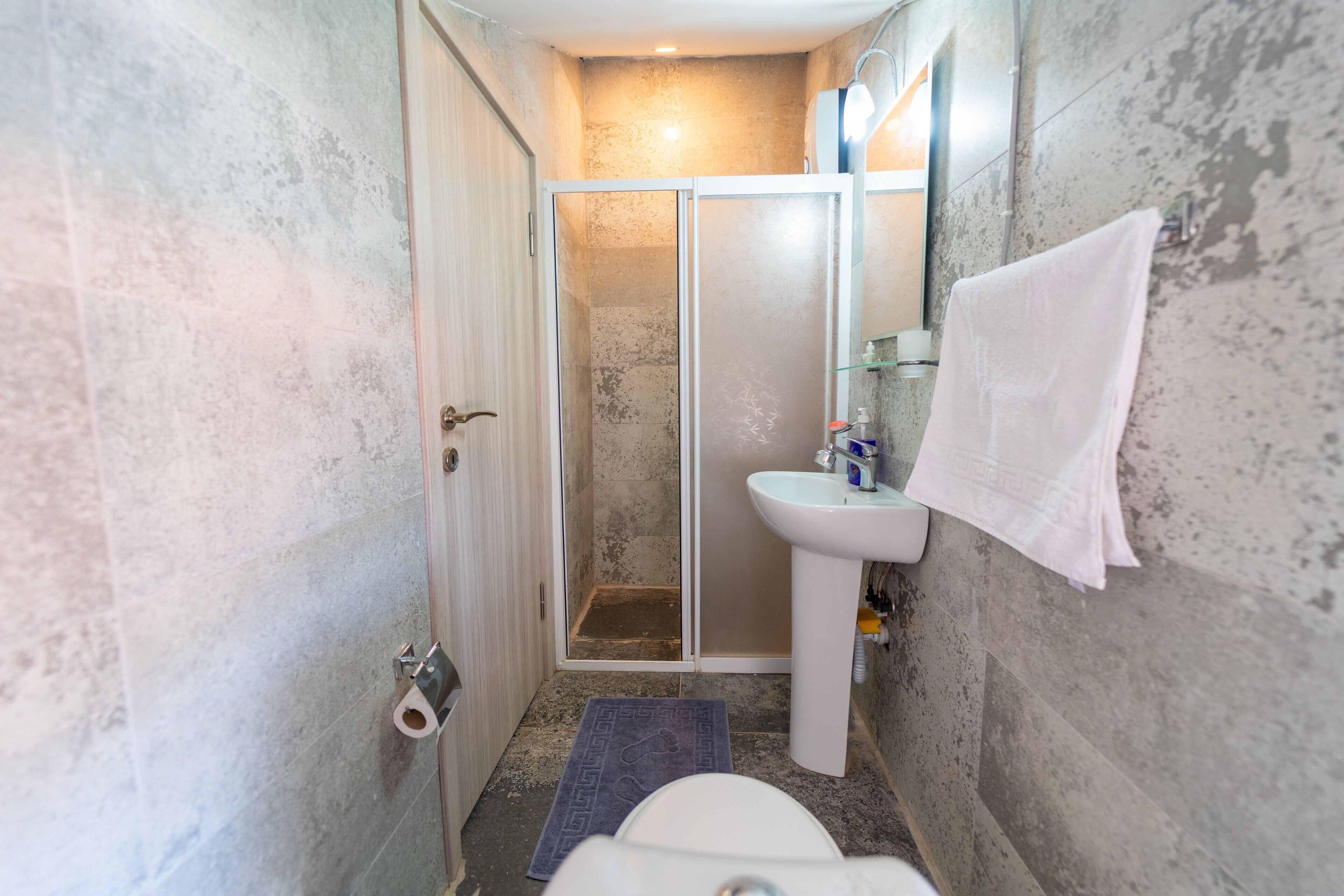 A compact bathroom with a shower, toilet, and sink.