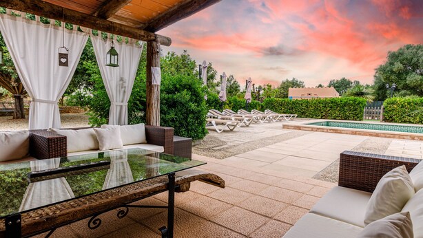An outdoor patio with a glass table, white cushioned seating, and a view of a swimming pool. - Quiet pool villa with chill out area, barbecue near Llucmajor, YourHouse Can Rosillo (LLucmajor)