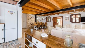 A wooden ceiling, a dining area with chairs and a table, a white refrigerator, and a patterned wall. - Quiet pool villa with chill out area, barbecue near Llucmajor, YourHouse Can Rosillo (LLucmajor)