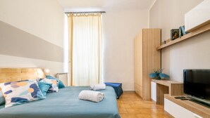 Une chambre à coucher avec un lit, une télévision, une armoire en bois et une fenêtre avec des rideaux.