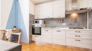Une cuisine moderne avec des meubles de couleur claire, un four à micro-ondes, un four traditionnel, un évier et une cuisinière à gaz.