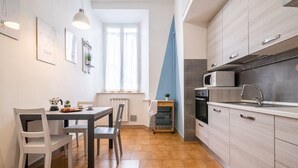 Une cuisine compacte avec un coin repas, équipée d’un four à micro-ondes, d’un four traditionnel et d’un évier.