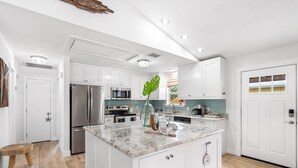 A modern kitchen with white cabinetry, stainless steel appliances, and a marble countertop. - New Reno! Optional htd private Pool! Close to Bch! Pet Friendly! Putting green! (Panama City Beach)