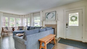 A living room with a sectional sofa, a wooden bench, a fireplace, and a door with a wreath.