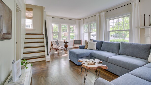 A spacious living room with a large sectional sofa, a wooden coffee table, and a staircase leading to another level.