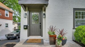 A house with a grey door, a brown doormat, and potted plants in front.