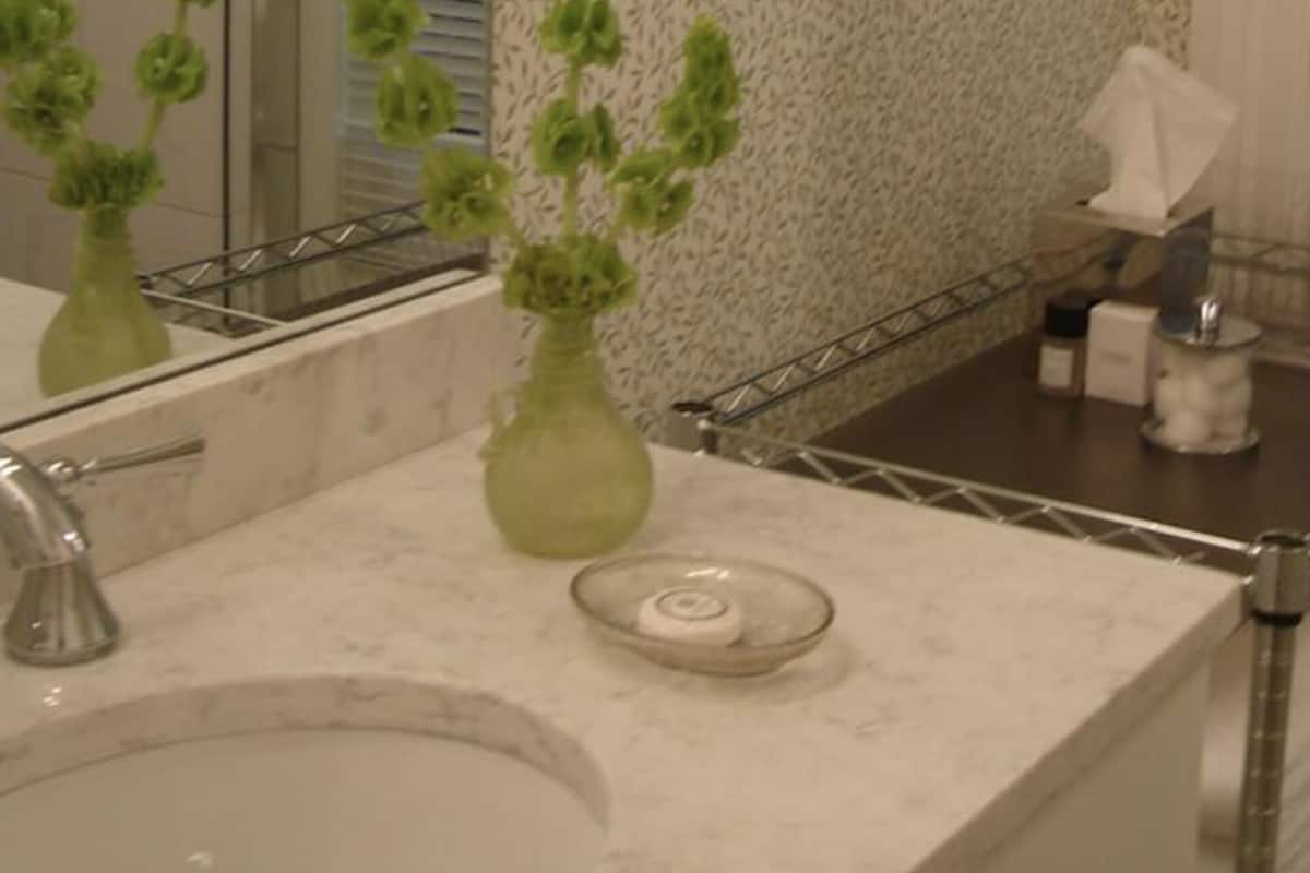 A bathroom with a marble sink, a green vase, a soap dish, and a towel rack.