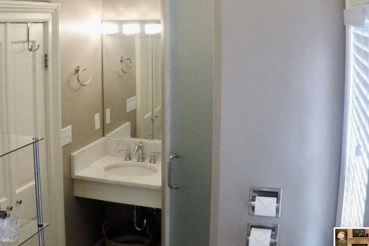 A bathroom with a glass shower enclosure, a sink, and a mirror.