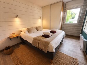 Ein modernes Schlafzimmer mit einem großen Bett, Nachttischlampen, einem Fenster und einem eingebauten Kleiderschrank.