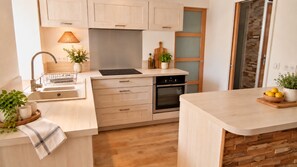 A modern kitchen with a built-in oven, a sink, and a countertop with a bowl of lemons.