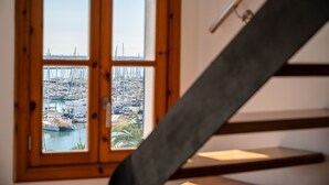Vista a través de una ventana con marco de madera, que da a un puerto deportivo con numerosos barcos.