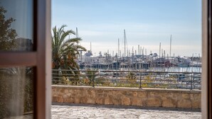 Un puerto deportivo con barcos amarrados, un muro de piedra y una palmera.