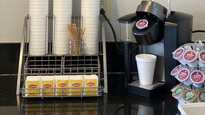 A coffee station with disposable cups, Lipton tea bags, and a coffee machine. - Harrington Welcome Inn (Harrington)
