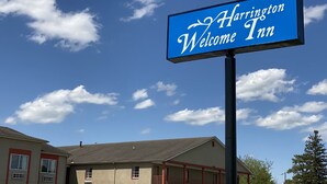 A Harrington Welcome Inn sign with a clear blue sky and clouds in the background. - Harrington Welcome Inn (Harrington)